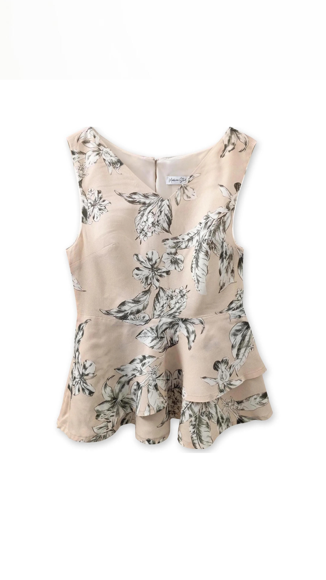 Close-up detail of the layered asymmetrical peplum hem on the beige floral linen blend blouse